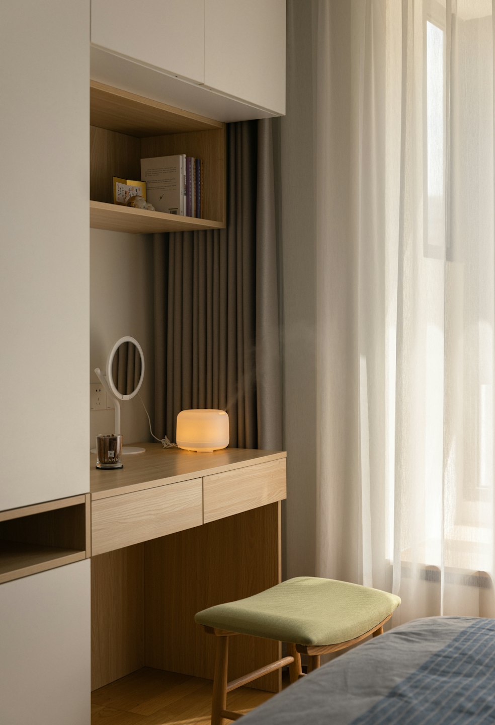 Minimalistische Arbeitsecke mit hellem Holzschreibtisch und Aroma-Diffusor.