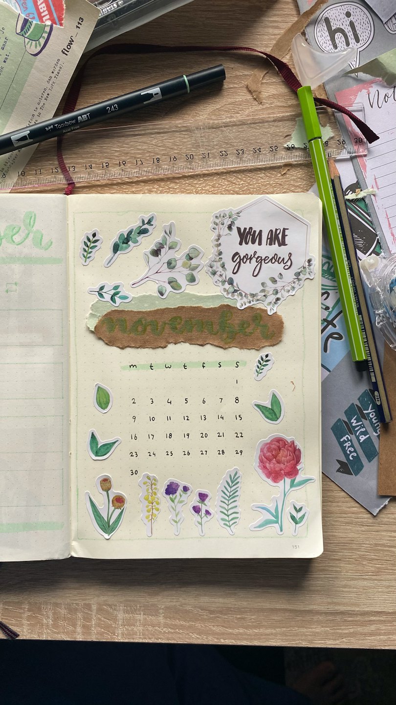 November-Kalender in einem offenen Bullet Journal mit floralen Stickern.