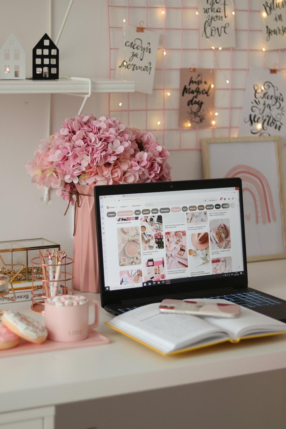 Ein Laptop auf einem Schreibtisch, umgeben von Blumen und Dekoration.