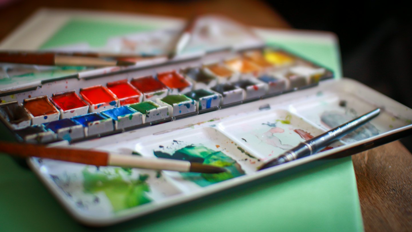 Aquarellfarben-Set mit Pinseln und gemischten Farben auf der Palette.