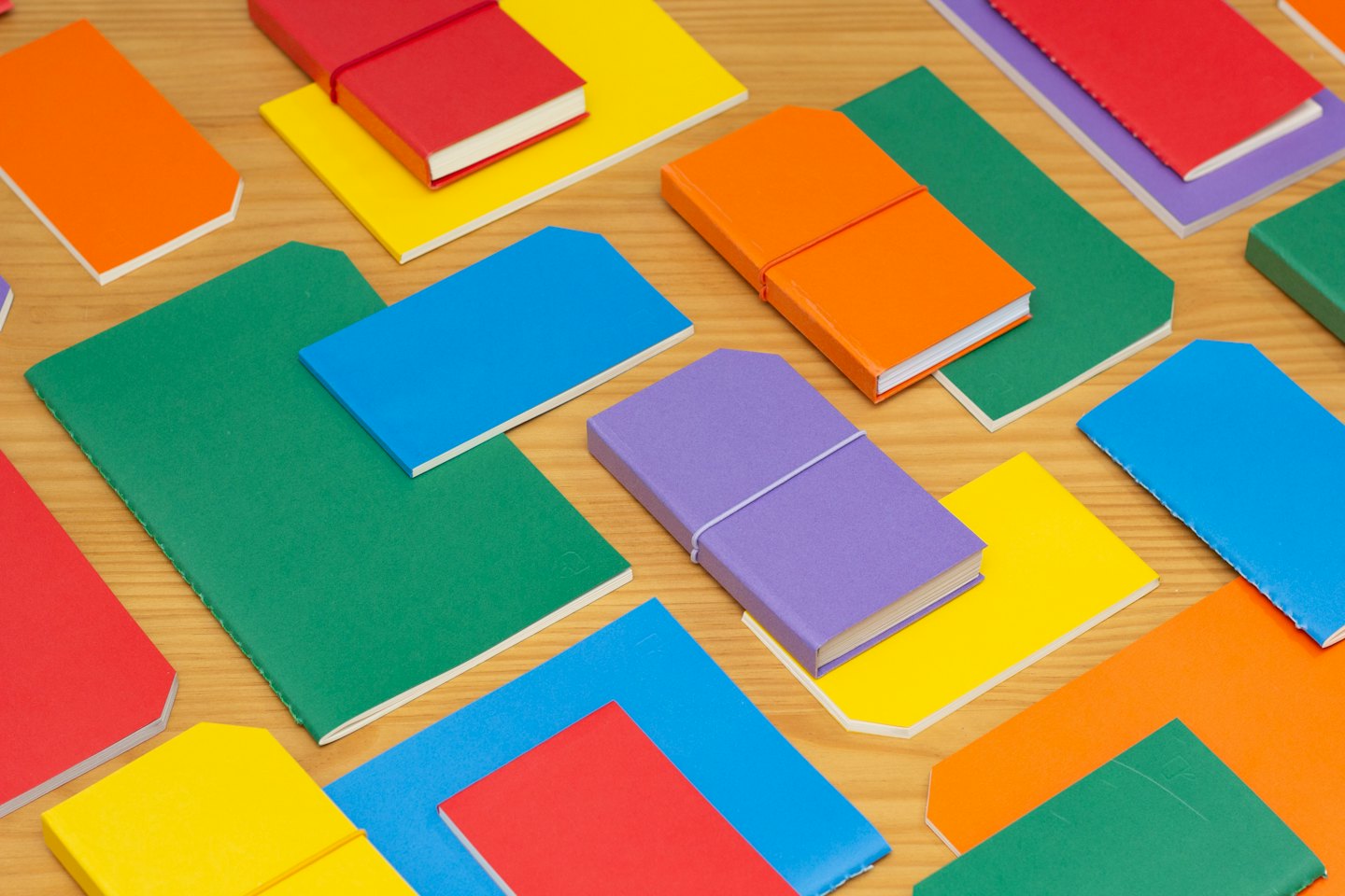 Bunte Notizbücher und Journale auf einem Holztisch verstreut.