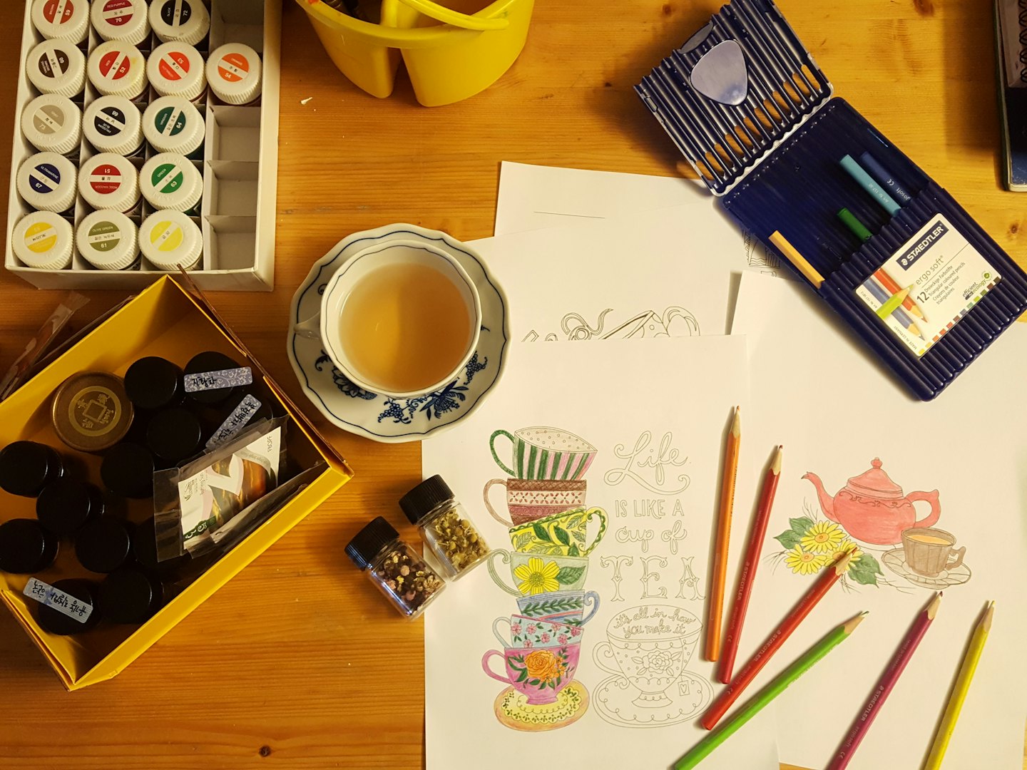 Künstlerbedarf und eine Teetasse auf einem Holztisch.
